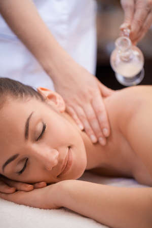 Beautiful woman having a wellness back massage  pretty woman laying on massage table and getting oil massageの写真素材
