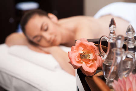 girl is laying on massage table  flower and bottle on tableの写真素材