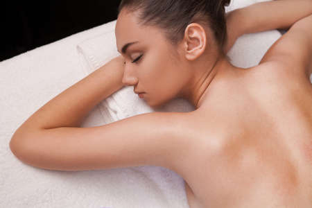 girl laying on massage table  white towel and bed under sleeping girlの写真素材