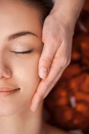 pretty face massage at the spa salon  girl laying on massage table and relaxingの写真素材