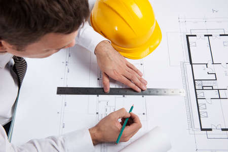 professional architect drawing construction plan. man sitting at table with pencil and rulerの写真素材