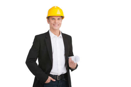 professional builder wearing helmet and smiling. man holding hands in pocket and papersの写真素材