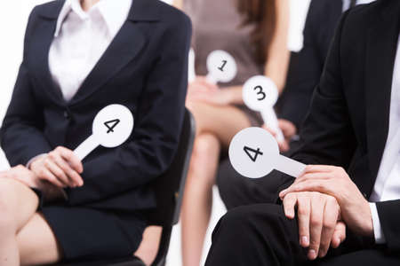 people wearing black suits voting. group of men and women holding numbers