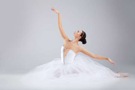 attractive young ballet dancer acting out. beautiful ballerina sitting forward splitの写真素材