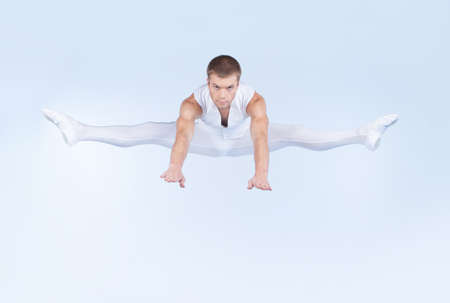 ballet dancer jumping on white background. handsome performer dancing ballet in studioの写真素材