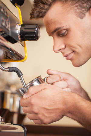 handsome young barista heating milk. attractive male making coffee and milkの写真素材