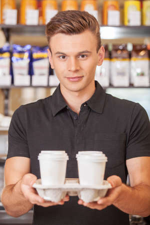 young handsome barista holding coffee. handsome worker making coffee with milkの写真素材