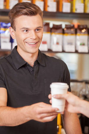 young handsome barista giving coffee. smiling male bartender flirting with girlの写真素材