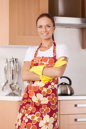 Beautiful young housewife cleaning the kitchen. attractive  housewife standing in apron at kitchen and smilingの写真素材