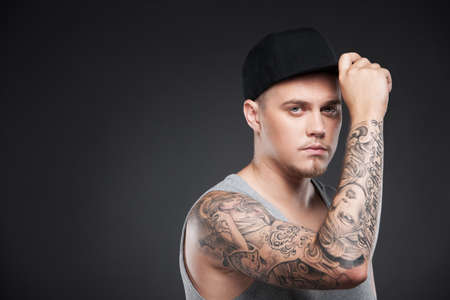 young cool guy holding hat. handsome man looking serious on blackの写真素材