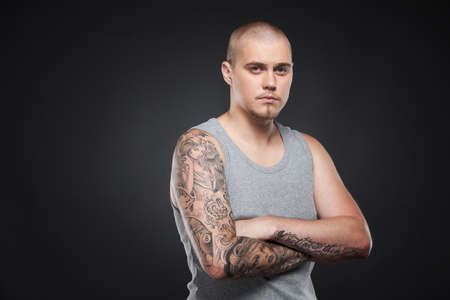 handsome young guy standing and looking. tattooed attractive man on black background の写真素材