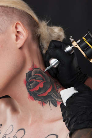 professional tattooist making rose tattoo. blond guy getting neck tattooの写真素材