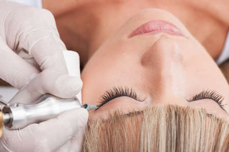 professional tattooist making permanent make up. beautiful girl laying closed eyesの写真素材