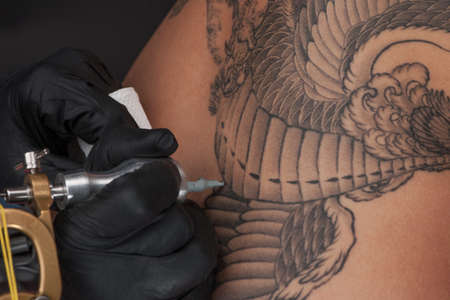 professional tattooist making back tattoo. studio made tattoo on male backの写真素材
