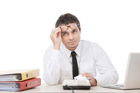 young business man removing glasses. male sitting at office desk and calculating の写真素材