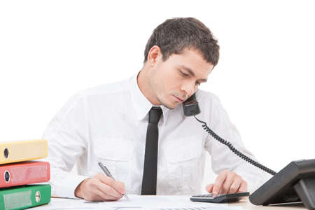 hardworking young man talking on phone. young businessman sitting at desk and writingの写真素材