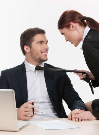 beautiful woman pulling man by tie. handsome man looking and smiling to womanの写真素材