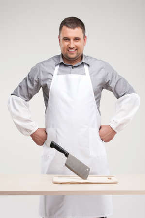 professional butcher smiling behind table. man standing with arms a-kimbo and in sleevesの写真素材