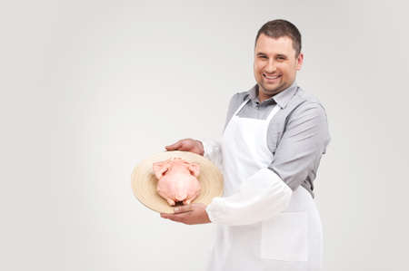 young handsome man holding plate. professional butcher in apron smiling and showing chickenの写真素材