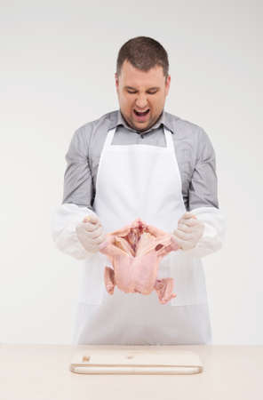 professional cook preparing chicken for meal. man holding chicken and tearing apartの写真素材