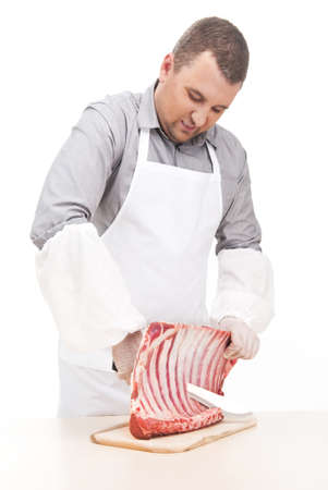 professional butcher cutting ribs on board. young man standing and cutting meatの写真素材