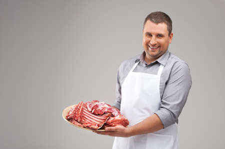 professional butcher smiling and holding raw meat. young chef demonstrating red meat の写真素材
