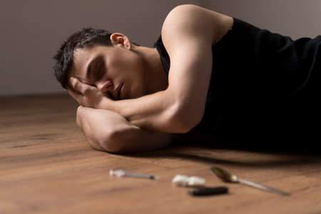 young handsome man lying on floor. wasted dude sleeping in bliss from drugs の写真素材