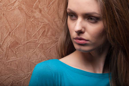 young woman leaning against wall. closeup of beautiful girl looking sadの写真素材