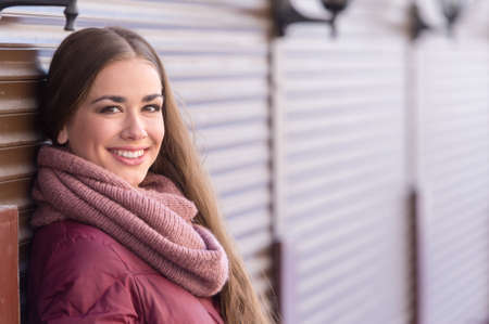 Beautiful woman leaning on brown wall. closeup of attractive brunette standing and smilingの写真素材
