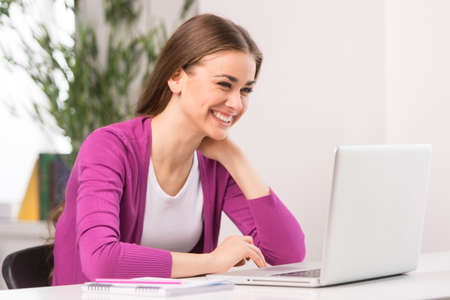 adult student girl sitting and studying. closeup of smiling girl using computerの写真素材