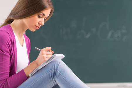 adult student girl sitting and writing. beautiful girl holding pen and thinkingの写真素材