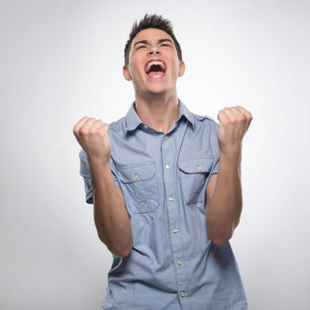 handsome young man shouts from joy. attractive male shows hands and fistsの写真素材