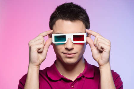 handsome young man watching movie. attractive male adjusting anaglyph glassesの写真素材