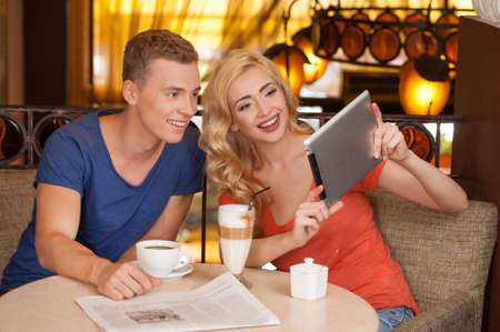 beautiful blond girl holding tablet. handsome guy looking at screen and smilingの写真素材