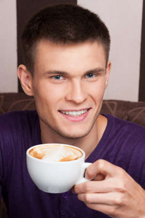 handsome young man close up picture. man drinking coffee in coffee shopの写真素材