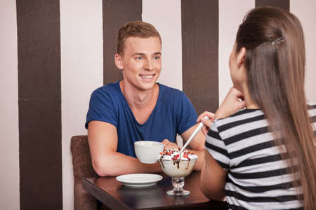 young man sitting with beautiful girl. beautiful couple drinking coffee in cafeの写真素材