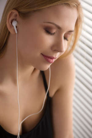 calm attractive blond listening music. beautiful girl closed eyes in delightの写真素材