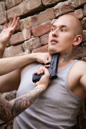 criminal holding gun at man neck. gangster pushing guy at wall and pointing gunの写真素材