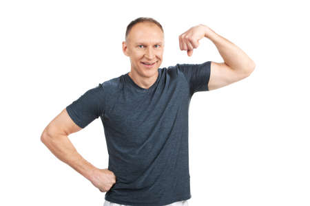 older man flexing muscles and smiling. caucasian guy standing on white and showing off