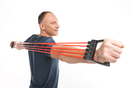 aged man exercising and doing fitness. athletic man using chest expander