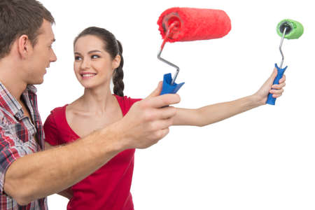 beautiful couple painting wall and smiling. girl and boy holding painting rollersの写真素材
