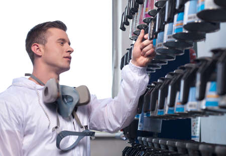 waist up of man selecting car paint. closeup of man wearing overall and working in shopの写真素材