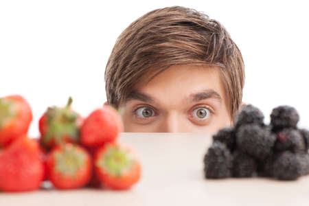 young man sitting under table and looking at fruits. closeup of guy eyes looking at fruits and smilingの写真素材