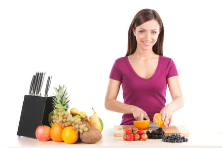 young girl cutting orange and smiling. closeup up of beautiful woman making saladの写真素材