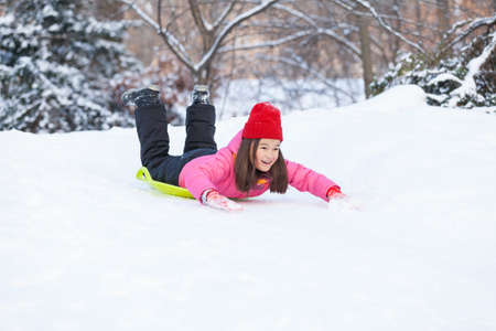 girl sliding on snow from hill fast. child lying on sledges and doing down fast