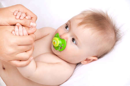 newborn baby lying on white bed. cute baby holding parent hand