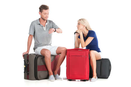 frustrated couple waiting departure with luggage. handsome man looking at watches and sittingの写真素材