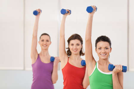 Aerobics class of women ligting weights. girls working out in gym with dumbbells flexing their arm...