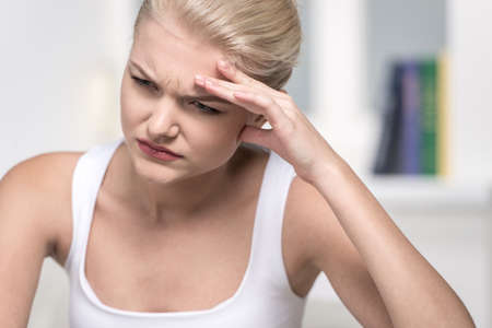 Close up Portrait of woman with headache. Teen woman holding her hand to head 