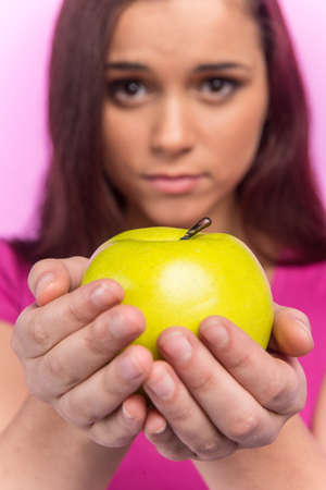 Young girl holding green apple. beautiful girl looking sad and blurの写真素材